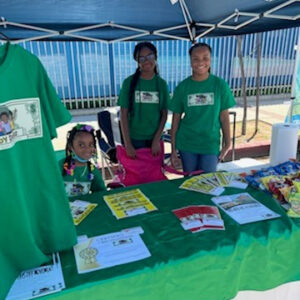 Three kids standing behind a vendor table